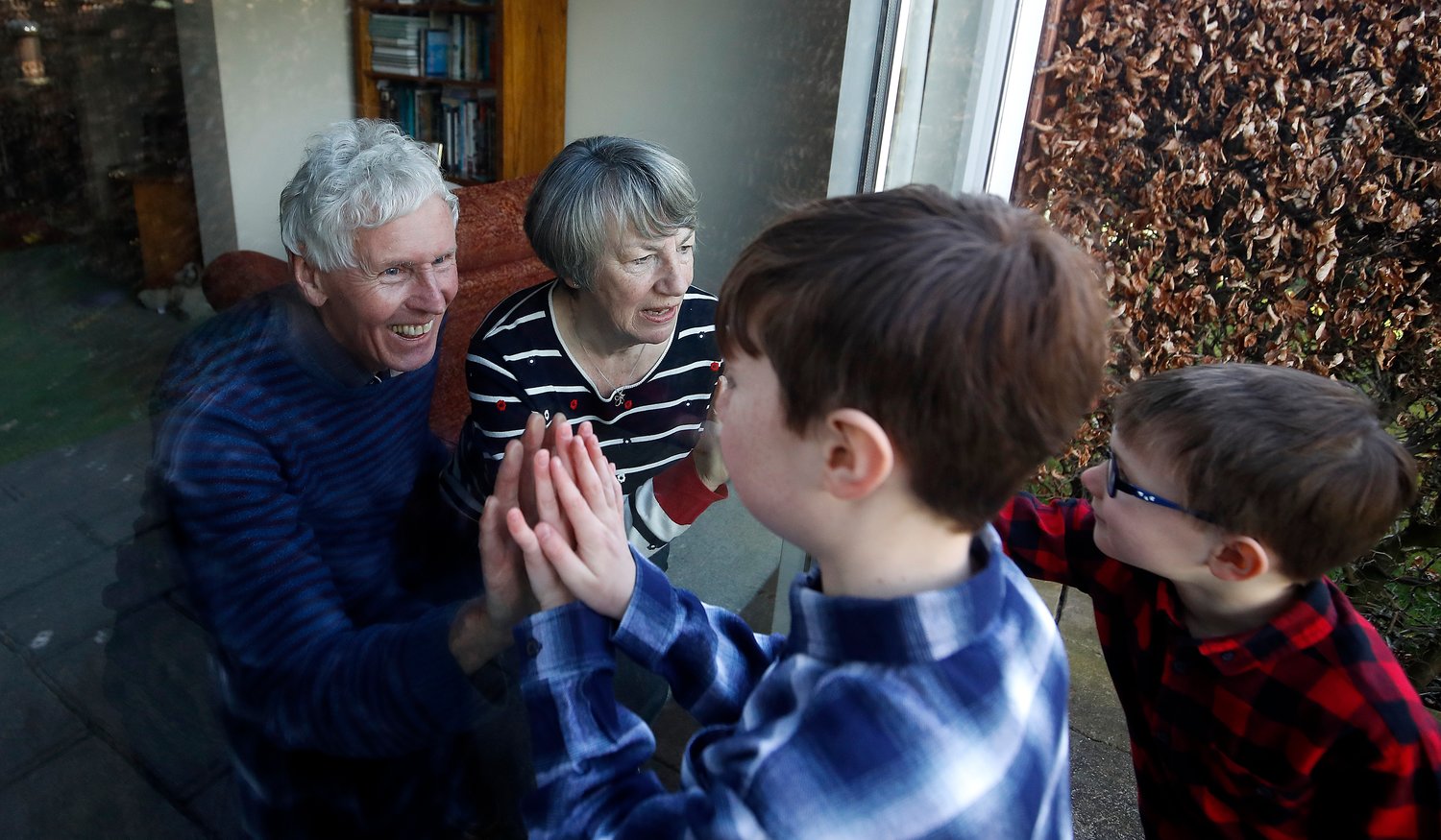 Ben and Isaac talk to their grandparents, Sue and Alan, through a window as they self-isolate at their home in Cheshire, England, March 22, 2020. (CNS photo/Martin Rickett, PA Images via Reuters) See POPE-ANGELUS-GRANDPARENTS July 27, 2020.
